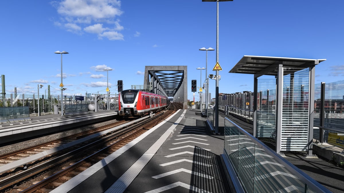 A modern train at Elbbrücken Station in Hamburg, showcasing futuristic architecture under a clear blue sky.